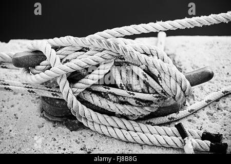 Nautical ropes tied around horn cleat on dock, close up in black and white. Key West harbor, Florida. Stock Photo