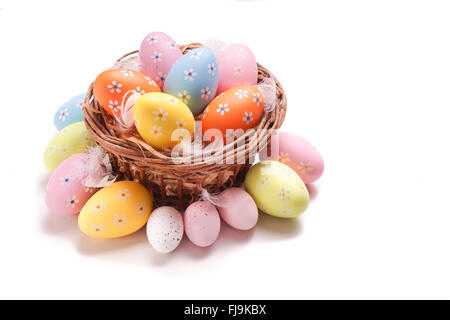 Colorful Easter eggs gathered in a basket, isolated on white Stock Photo