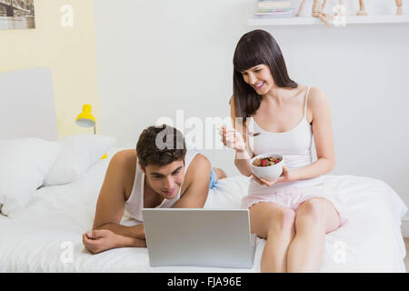 Young couple looking at laptop on bed Stock Photo