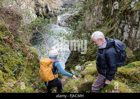 Hikers walking down rocky path into Lledr Gorge in Snowdonia National Park near Dolwyddelan, Conwy, North Wales, UK, Britain Stock Photo
