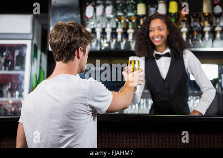 Barmaid serving beer to man Stock Photo