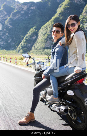 Young Chinese couple riding motorcycle together Stock Photo