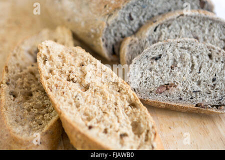 Close-up of wholemeal or whole grain bread with olives hand-sliced and on a bread board Stock Photo