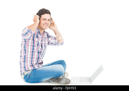 Man with headphones sitting on the floor using laptop Stock Photo