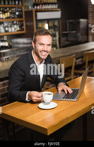 Handsome man using laptop and having a coffee Stock Photo