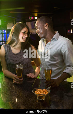 Couple looking at each other while having beer at bar counter Stock Photo