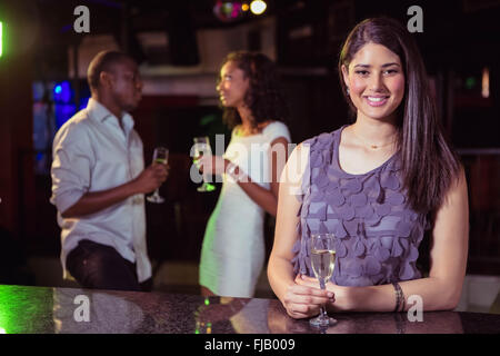 Young woman having champagne in bar and her friends talking Stock Photo