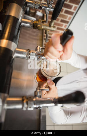 Handsome barman pouring a pint of beer Stock Photo