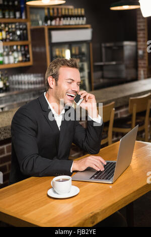 Thoughtful man using laptop and smartphone Stock Photo