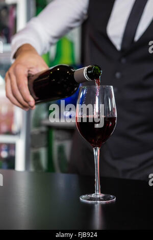 Mid section of bartender pouring red wine in a glass Stock Photo