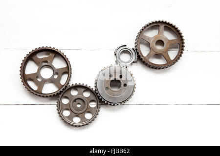 Interlocking industrial  cogwheels on white wooden background Stock Photo