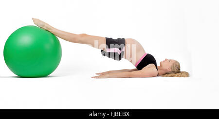 Pregnant woman using yoga ball performing hip raise exercise. Stock Photo