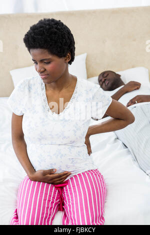 Pregnant woman sitting on bed Stock Photo