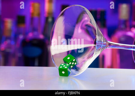 Green dice in cocktail glass with bar on back Stock Photo