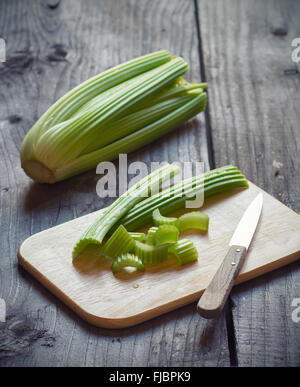 Fresh green celery stems on wooden cutting board closeup Stock Photo