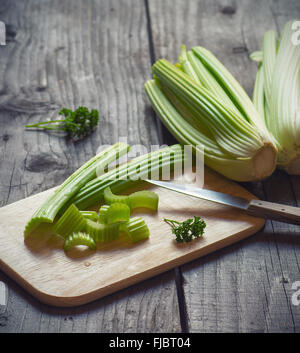 Fresh green celery stems on wooden cutting board closeup Stock Photo