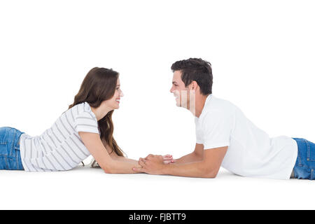 Happy couple lying on the floor looking to each other and holding hands Stock Photo