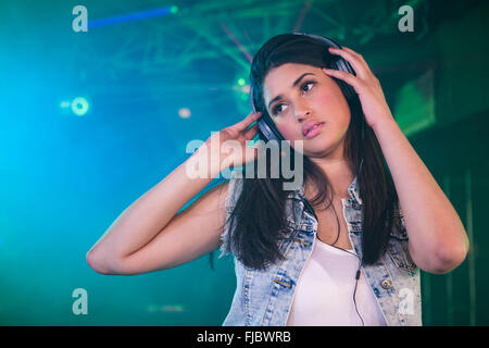 Pretty female DJ listening music on headphone Stock Photo