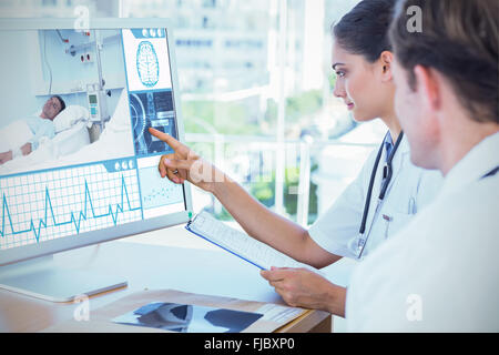 Composite image of doctor pointing at the screen of a computer Stock Photo