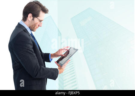 Composite image of businessman standing while using a tablet pc Stock Photo