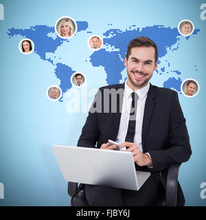 Composite image of happy businessman with laptop using smartphone