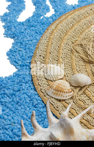 Straw hat with a  seashells are lying on a little blue stones forming a wave isolated on the white. Stock Photo