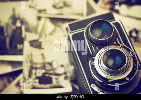 Vintage photo of the old family photos lying on a table. The old camera is lying on an old photos. Stock Photo