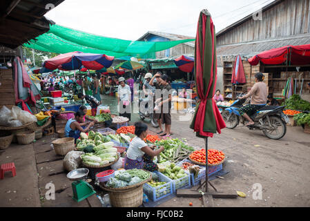 Zegyo Market Women Vendors Produce Baskets Mandalay Myanmar | MANDALAY, Myanmar — Women vendors in traditional longyi sell cabbages, tomatoes, and leafy greens from woven baskets in the open-air streets bordering the Zegyo (Zay Cho) market. Across Myanmar's inland fisheries and markets, women dominate the fresh-produce and fish trade; at nearby Ayeyarwady fisheries the FAO records roughly 1,500 village women each reselling fixed daily allocations at about a 15 percent markup. Stock Photo
