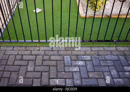 Artificial grass / astro turf meets a paved street path on a new build housing estate. Bicester, Oxfordshire, England Stock Photo