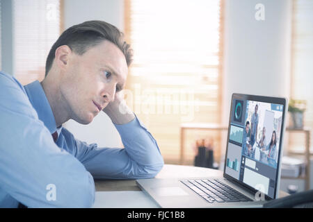 Composite image of focused businessman looking at laptop Stock Photo