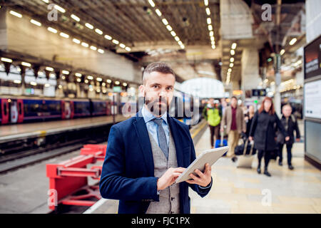 Close up, hipster businessman with tablet, train station Stock Photo
