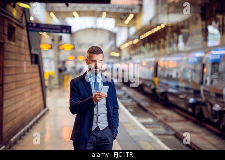 Hipster businessman with smartphone, waiting at the train platfo Stock Photo