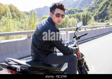 Young Chinese man riding motorcycle Stock Photo