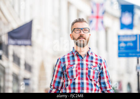 Hipster man with eyeglasses shopping in streets of London Stock Photo