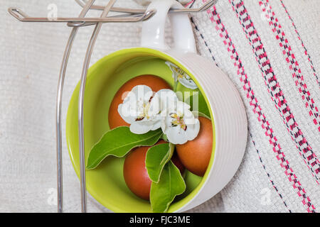 The dyed red Easter eggs and Apple blossoms are installed in large ceramic cups. Stock Photo