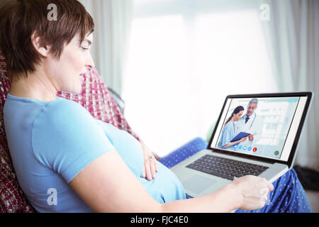 Composite image of pregnant woman using her laptop Stock Photo