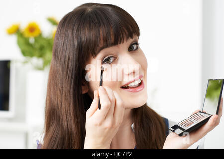 Young Woman Applying Eye Make Up At Home Stock Photo