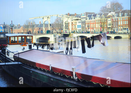 Drying clothes on a barge. Famous Skinny bridge on a background. Amsterdam, Holland Stock Photo