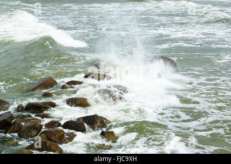 stones lie in a raging sea under blows of big waves Stock Photo