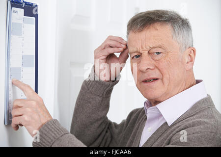 Confused Senior Man With Dementia Looking At Wall Calendar Stock Photo