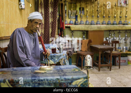 Muslim man smoking from a water pipe in a small restaurant at night. Stock Photo