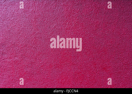 contrastly lit crimson rough plastered painted wall Stock Photo