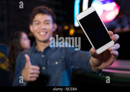 Young Chinese man showing smart phone at music festival Stock Photo