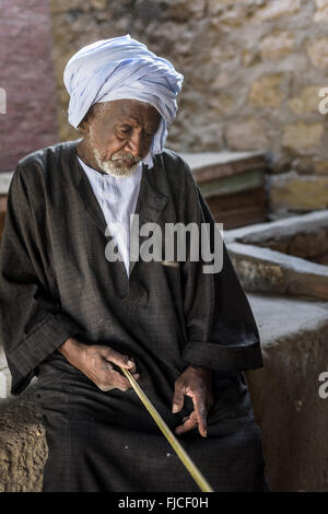Old man with a turban an a stick  at a camel market. Stock Photo