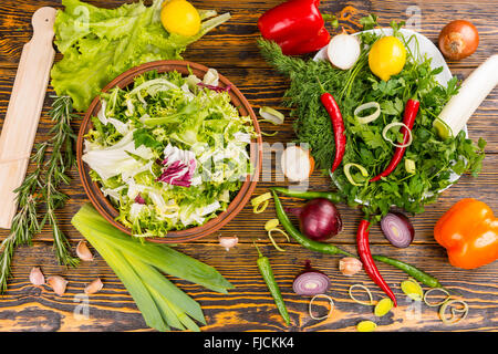 Top down view of rosemary, lettuce, leek, onion, peppers, lemon and other delicious ingredients on wooden table Stock Photo