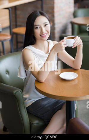 Young Chinese woman drinking coffee in café Stock Photo