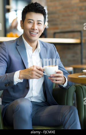 Chinese businessman drinking coffee in café Stock Photo