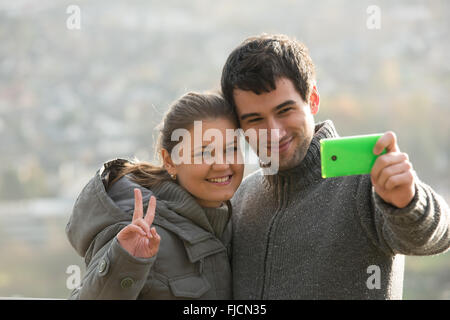 young couple, man and woman in front of Rheine river, Germany,makes selfie, photograph with smart phone Stock Photo