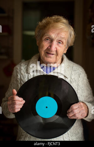 Old woman with vinyl disc in her hand. Record. Stock Photo