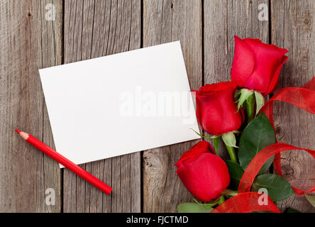 Red roses and greeting card over wooden background. Top view with copy space Stock Photo